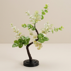 Artificial plant with green leaves and white flowers on a beige background