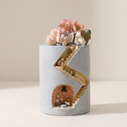 Decorative concrete vase with a miniature staircase and animal figurines on a neutral background