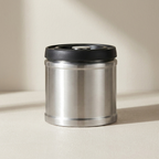 Stainless steel thermos with black lid on a beige background