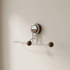 Wall-mounted metal hook with wooden knobs on a beige wall