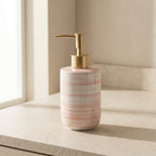 Ceramic soap dispenser with gold pump on a neutral background