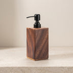 Wooden soap dispenser with black pump on a beige surface