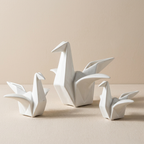 Three white ceramic swan sculptures on a beige background