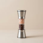 Silver pepper grinder with Himalayan salt and black pepper on a beige background