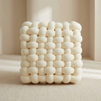 White woven cube-shaped pillow on a neutral background