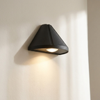 Black triangular wall light fixture on a beige wall