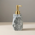 Marble-textured soap dispenser with gold pump on a neutral background