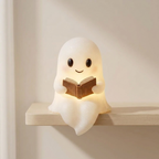 Ghost-shaped night light reading a book on a shelf