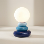 Table lamp with a white bulb and blue cylindrical base on a neutral background