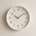 White wall clock with brown hands on a beige background