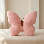 Pink butterfly-shaped pillow on a light surface with a neutral background