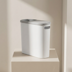 White trash bin with gray lid on a beige surface