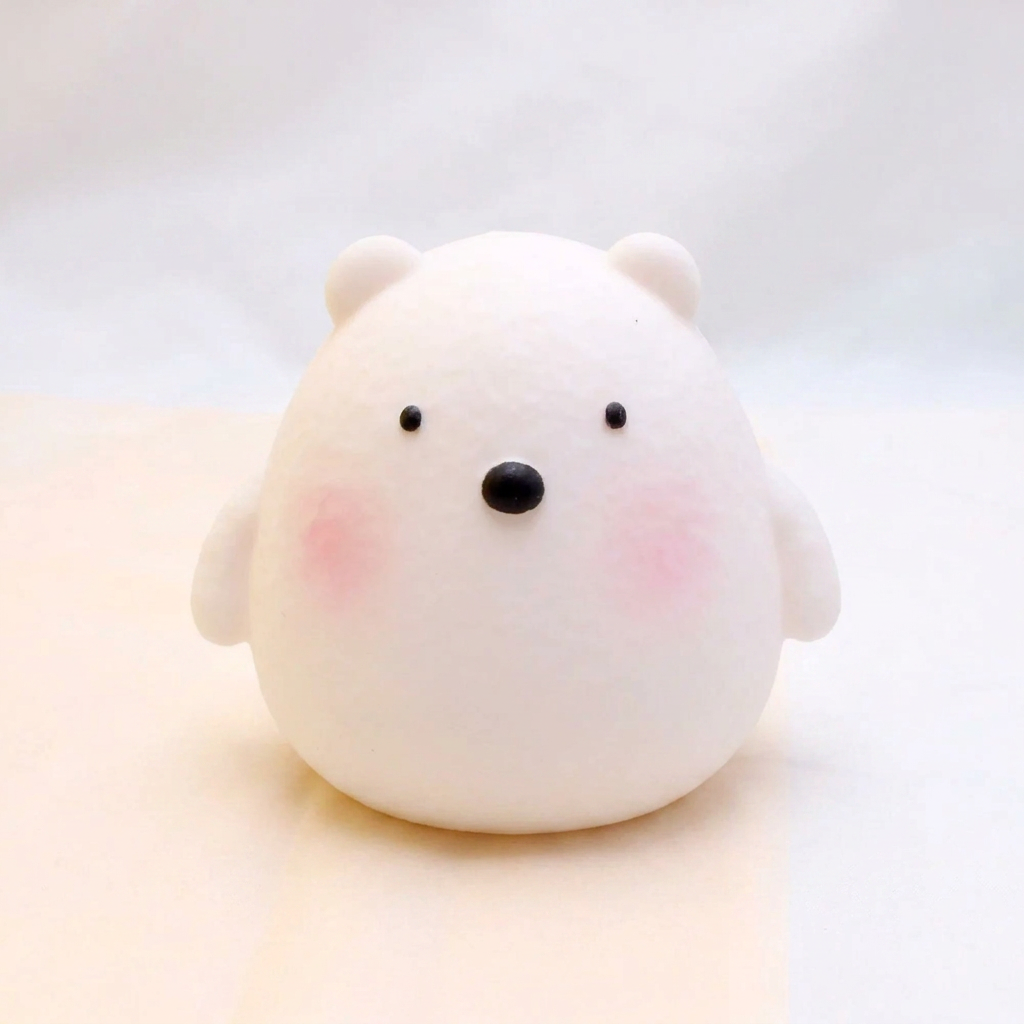 White bear-shaped object with black eyes and pink cheeks on a light background