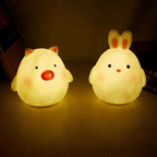 Two cute animal-shaped night lights on a dark surface.
