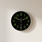 Wall clock with black face and green numbers on a light beige background