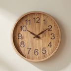 Wooden wall clock with brown hands on a beige background