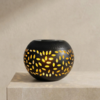 Black decorative bowl with yellow cut-out patterns on a beige background