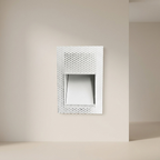 Decorative wall mirror with a geometric pattern on a beige wall.