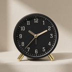 Black clock with gold hands on a beige background