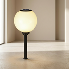 Solar-powered garden lamp with a glowing yellow light on a neutral background