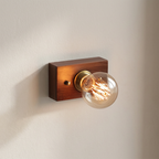 Wooden wall sconce with a lit Edison-style bulb on a neutral background