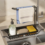 A black metal kitchen sink towel rack and basket organizer mounted over a stainless steel sink. The rack holds a blue and white striped towel, a soap dispenser bottle, a scrubber, and a yellow sponge.