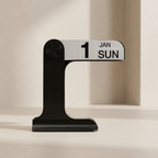A modern black and white flip calendar table displaying '1 JAN SUN' on a minimalist beige background.
