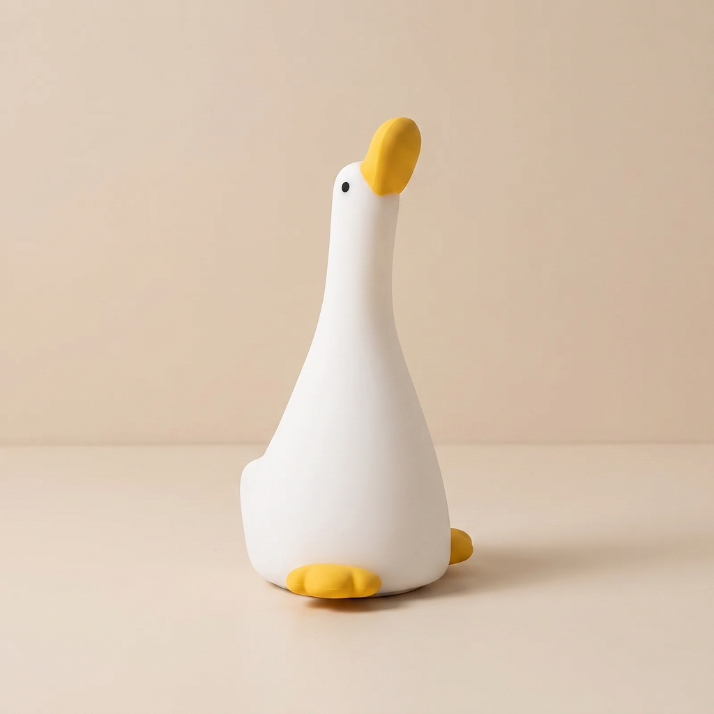 A white goose-shaped night light with a yellow beak, black eye, and yellow feet, sitting on a beige surface against a matching beige background.