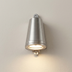 A modern wall-mounted cone-shaped light fixture with a brushed silver metal finish, shown illuminated against a plain off-white wall.