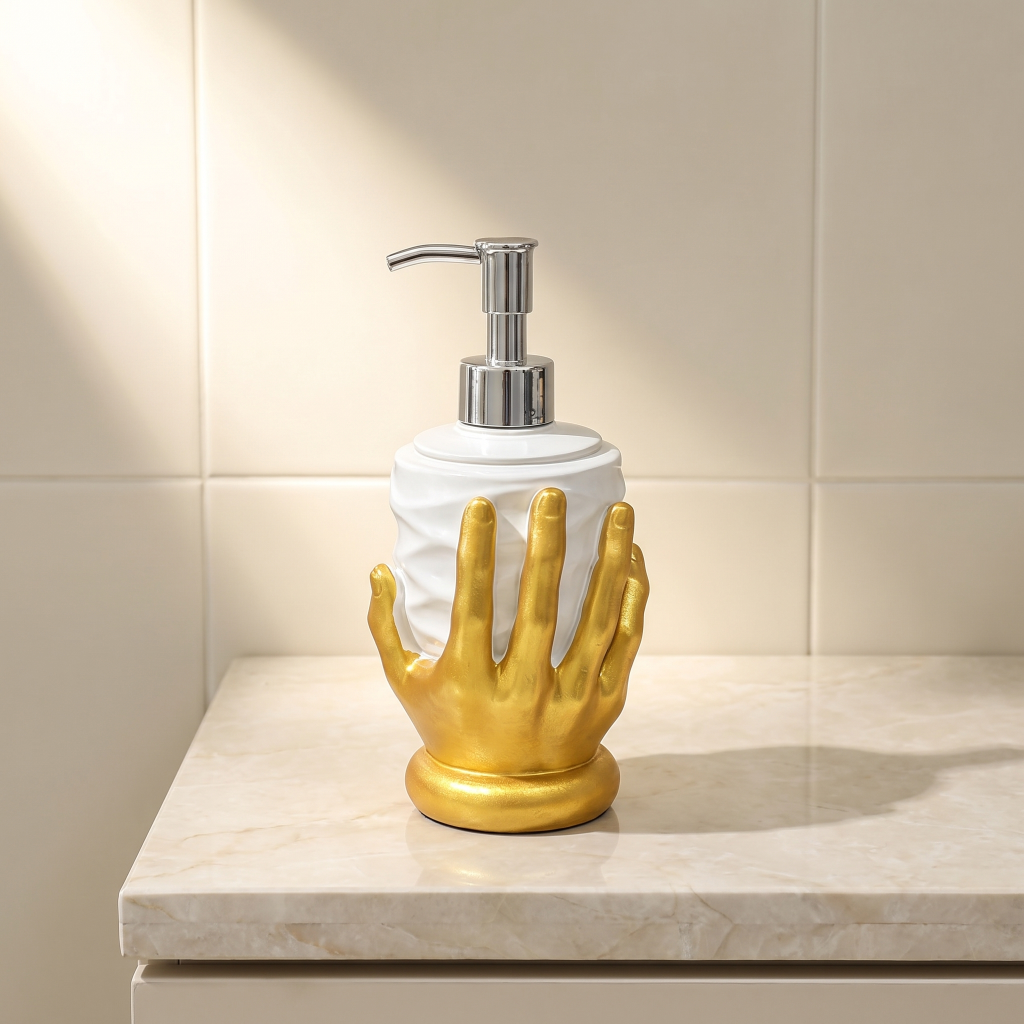 A bathroom soap dispenser with a white cylindrical bottle and a metallic gold hand-shaped base, set on a light marble countertop against a beige tiled wall.