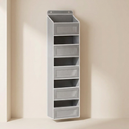 A tall, narrow gray wall-mounted organizer with six open shelves and four front drawer compartments, shown against a warm beige wall.