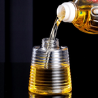 Clear ribbed plastic bottle with a threaded neck, shown partially filled with golden liquid, while a bottle of the same oil pours into it against a black background.
