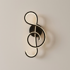 A modern wall-mounted light fixture shaped like a treble clef, with glowing white illuminated tubing and a matte black metal base and circular backplate, shown against a plain light gray wall.
