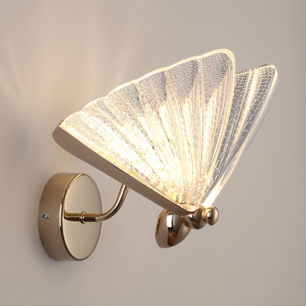 A modern wall-mounted butterfly-shaped light fixture with a glowing textured glass wing shade and polished brass hardware, shown against a plain light gray wall.