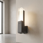 Modern wall-mounted sconce with a frosted rectangular glass shade and a matte black metal base, shown lit on a textured beige wall in an interior setting.