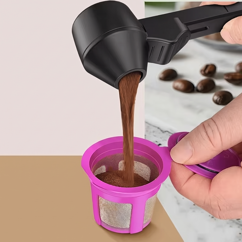 A hand holds a black coffee dripper above a bright pink reusable coffee filter cup, pouring coffee into it. A few coffee beans sit on a marble surface in the background.
