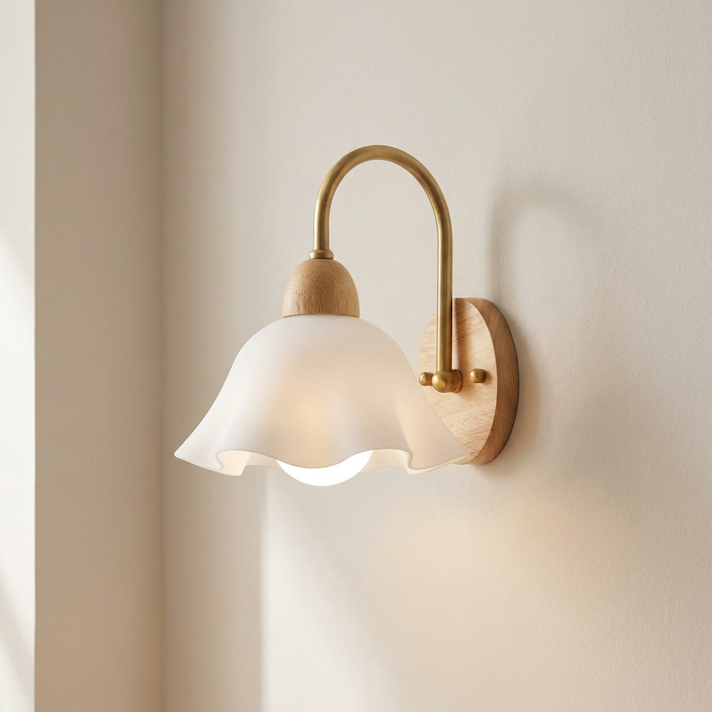 A wall-mounted sconce with a warm brass arched arm, a white fluted glass shade, and light natural wood accents, shown lit against a beige wall.