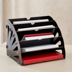 A black and silver metal document organizer with multiple angled shelves, shown holding white and red paper folders on a light beige tabletop against a neutral background.