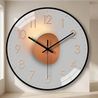 A large round wall clock with a white face, black outer rim, black hands, and gold-toned numerals and center medallion, mounted on a beige wall in an interior setting.