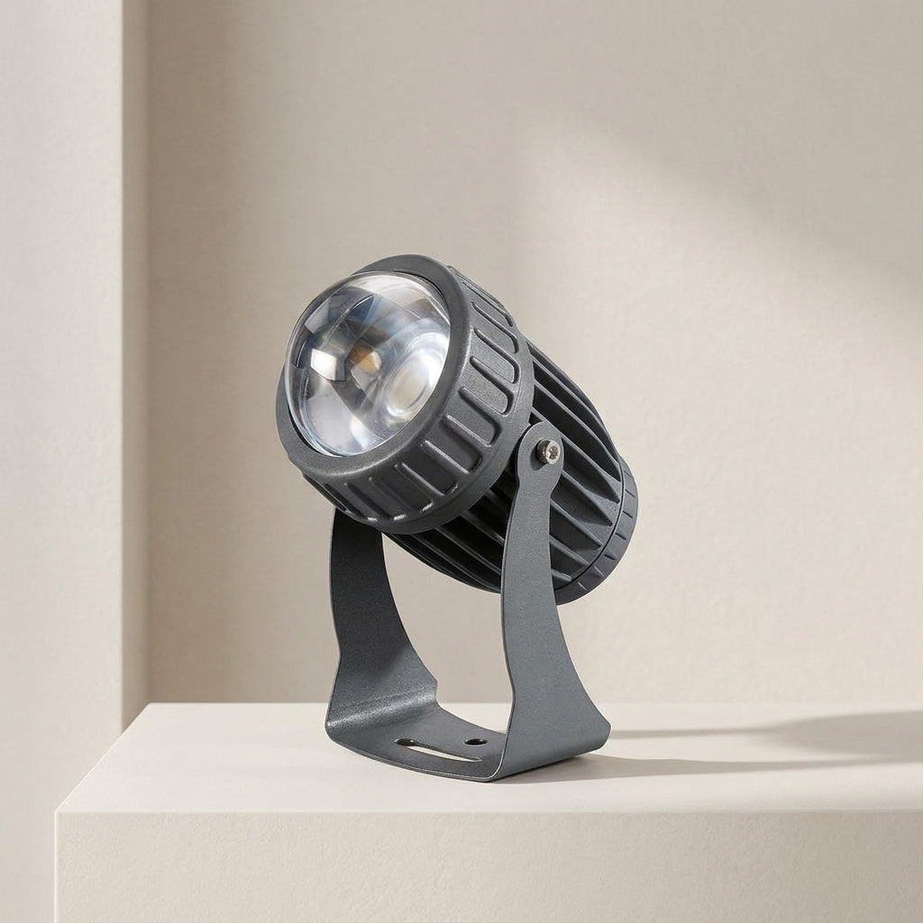 A modern dark gray LED spotlight with a ribbed metal housing and adjustable bracket, shown on a minimalist beige platform against a neutral background.