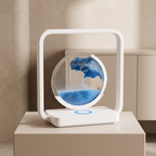 A modern white magnetic liquid marble clock with a blue and white swirling pattern, displayed on a beige pedestal in a minimalist room setting.