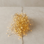 A tangled bundle of warm white fairy string lights on a light beige textured surface with a neutral background.