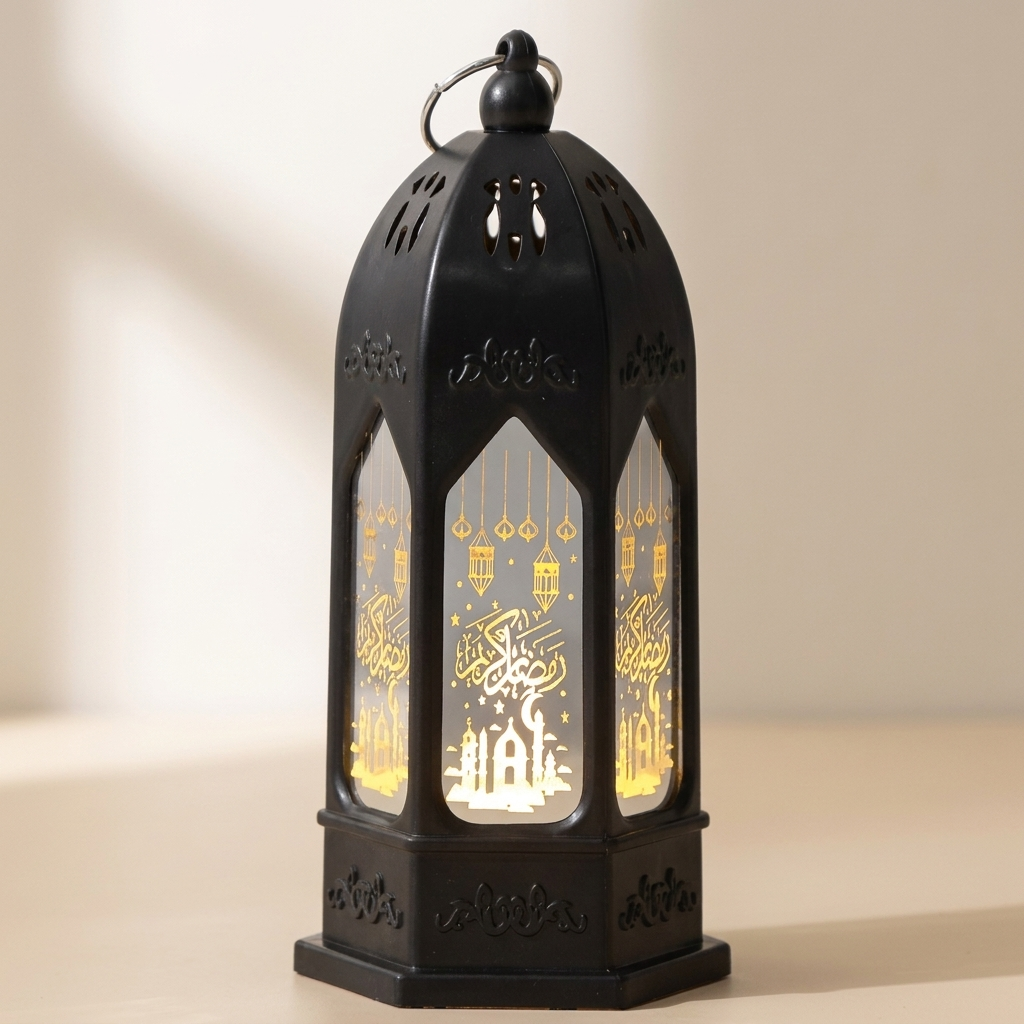A black metal lantern with intricate cutout details and warm yellow LED lighting inside, featuring illuminated Arabic calligraphy and a tree of life design, set against a soft beige background.