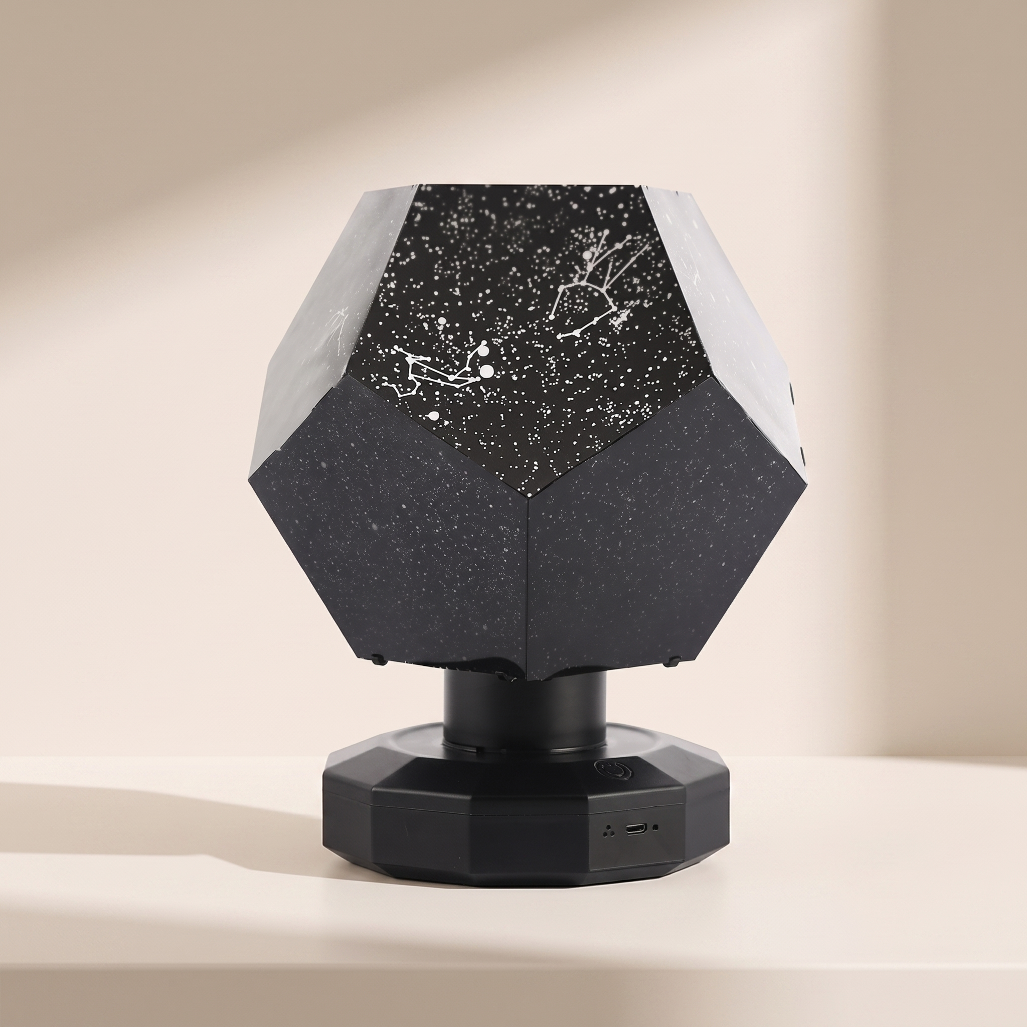 A faceted black and white table lamp with a geometric, diamond-like shape. The top half of the shade is black with white speckles and white constellation line art, while the bottom half is solid black.