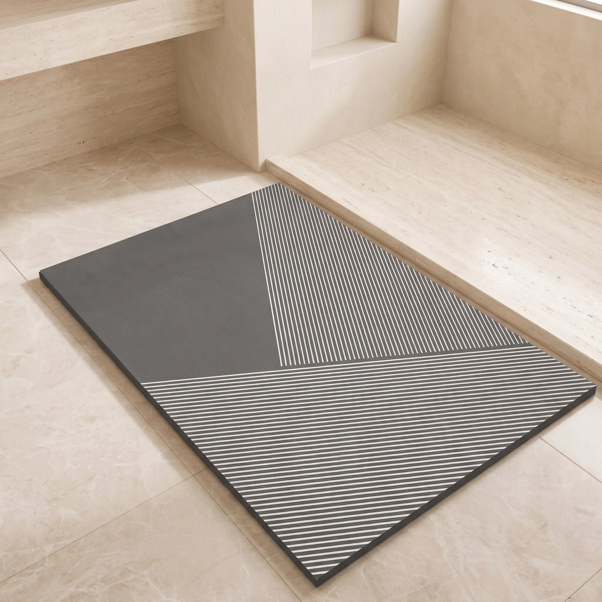A rectangular gray mat with a geometric pattern of solid dark gray and white diagonal stripes, placed on a light beige stone floor in a minimalist interior setting.