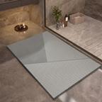 A rectangular floor mat or rug with a modern geometric pattern, shown in a styled bathroom setting with gray marble-look tiles and a glass shower door.