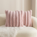 A pink ribbed plush throw pillow resting on a cream boucle armchair with a white faux-fur blanket.