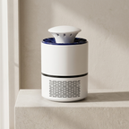 A modern white cylindrical device with a dark blue top ring and black vent grilles, sitting on a light beige stone ledge against a textured beige wall.