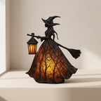 A witch figurine with a glowing tree-patterned dress and lantern, displayed on a light beige shelf against a neutral background.