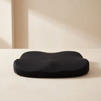 A black contoured memory foam neck pillow resting on a light beige surface against a matching beige background.